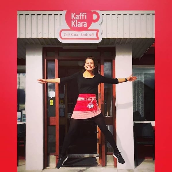 Una persona de pie frente a un edificio con un letrero que dice "Kaffi Klara - Cafetería de libros".