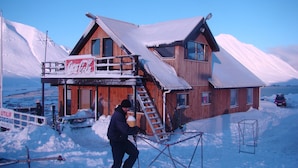Ein Holzhaus mit einem Coca-Cola-Schild, einer Seilbahn und einer Leiter, die zu einem zweiten Stock führt.