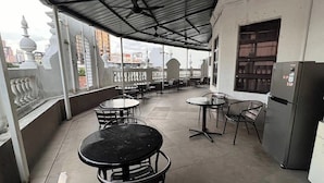 Una terrazza sul tetto con tavoli e sedie, un frigorifero e vista sulla città.