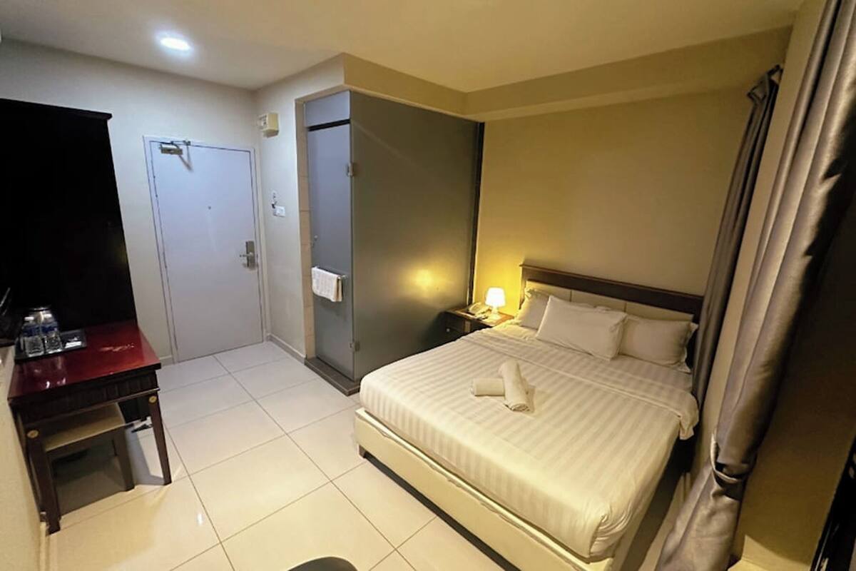 A hotel room with a bed, a desk, a wardrobe, and a bathroom door.