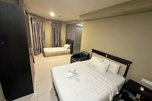 A hotel room with two beds, a desk, a chair, and a wardrobe. - Hotel AL Amin (Kuala Lumpur)