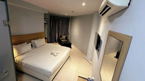 Una camera d'albergo con un letto, un comodino, un condizionatore d'aria e uno specchio.