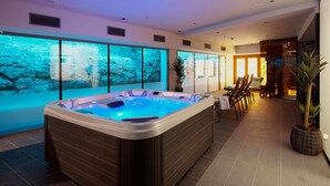 Un área de spa moderna con una bañera de hidromasaje, un espacio de relajación y un gran acuario.