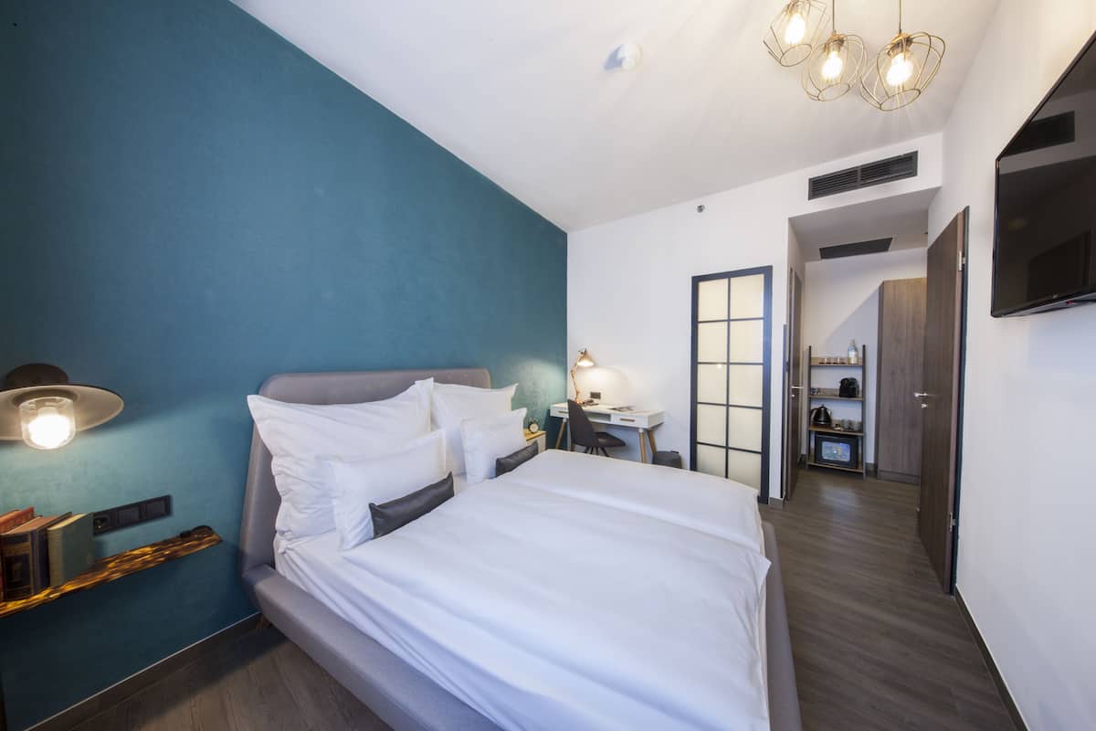 Una habitación de hotel moderna con una cama grande, un escritorio y una televisión.