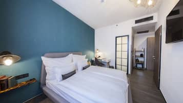 A modern hotel room with a large bed, a desk, and a TV.