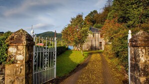 Un sendero rural que lleva a un edificio de piedra con una reja de metal.