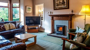 Un salón acogedor con chimenea, sofás de cuero, un televisor y una mesa de centro de madera.