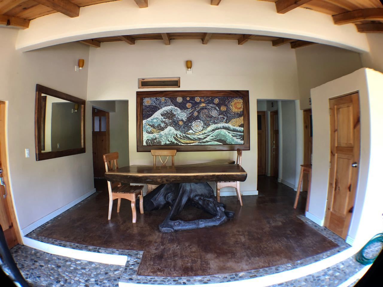 Uma sala de jantar com uma pintura grande, móveis de madeira e piso lustroso.