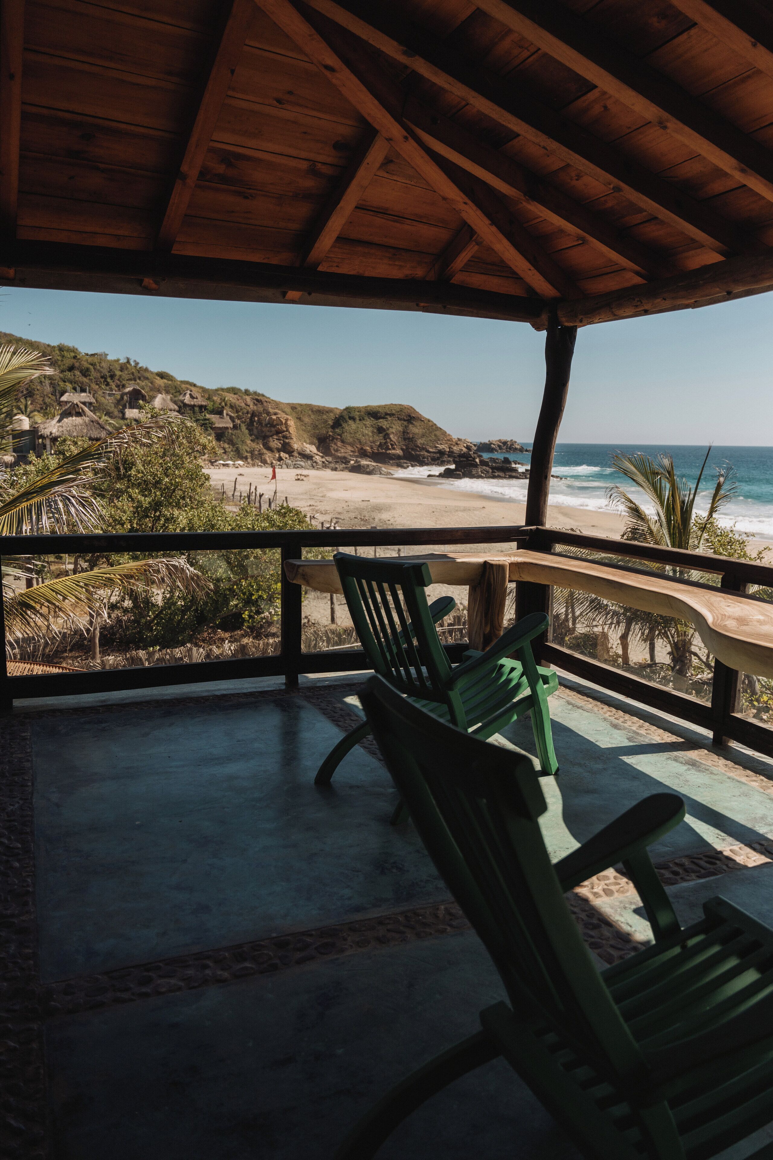 Un espacio de estar al aire libre cubierto con vista a la playa y al océano.