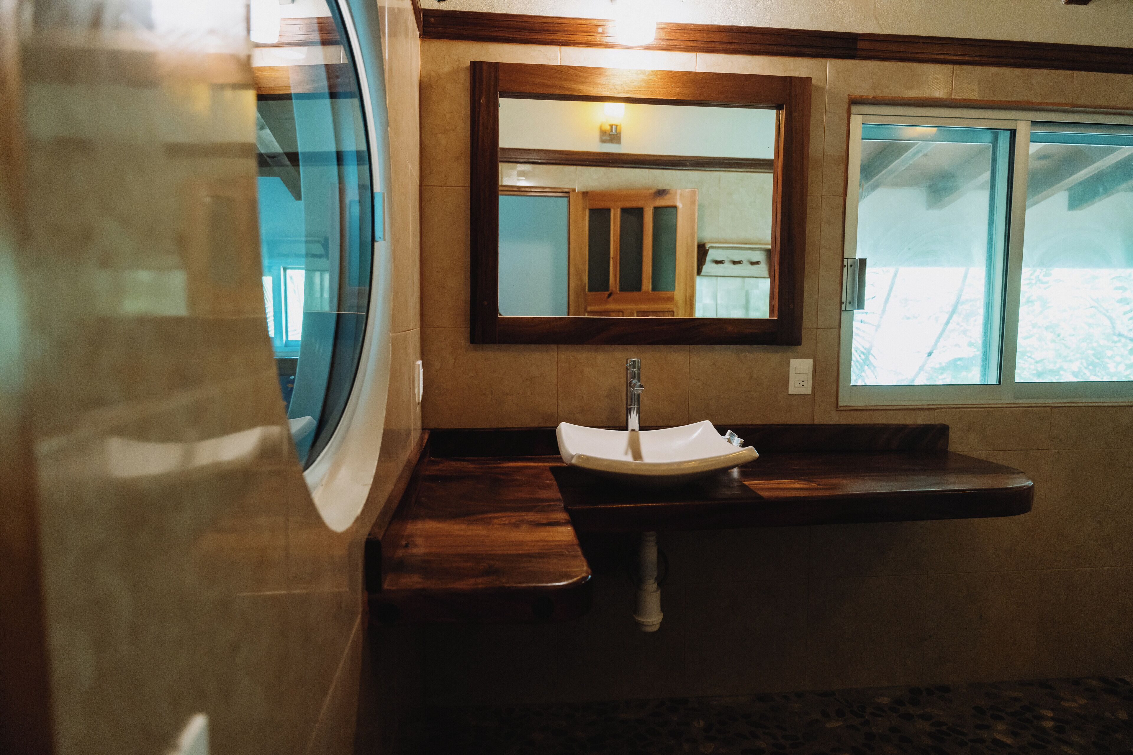 A bathroom with a sink, mirror, and window.