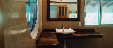 A bathroom with a sink, mirror, and window.