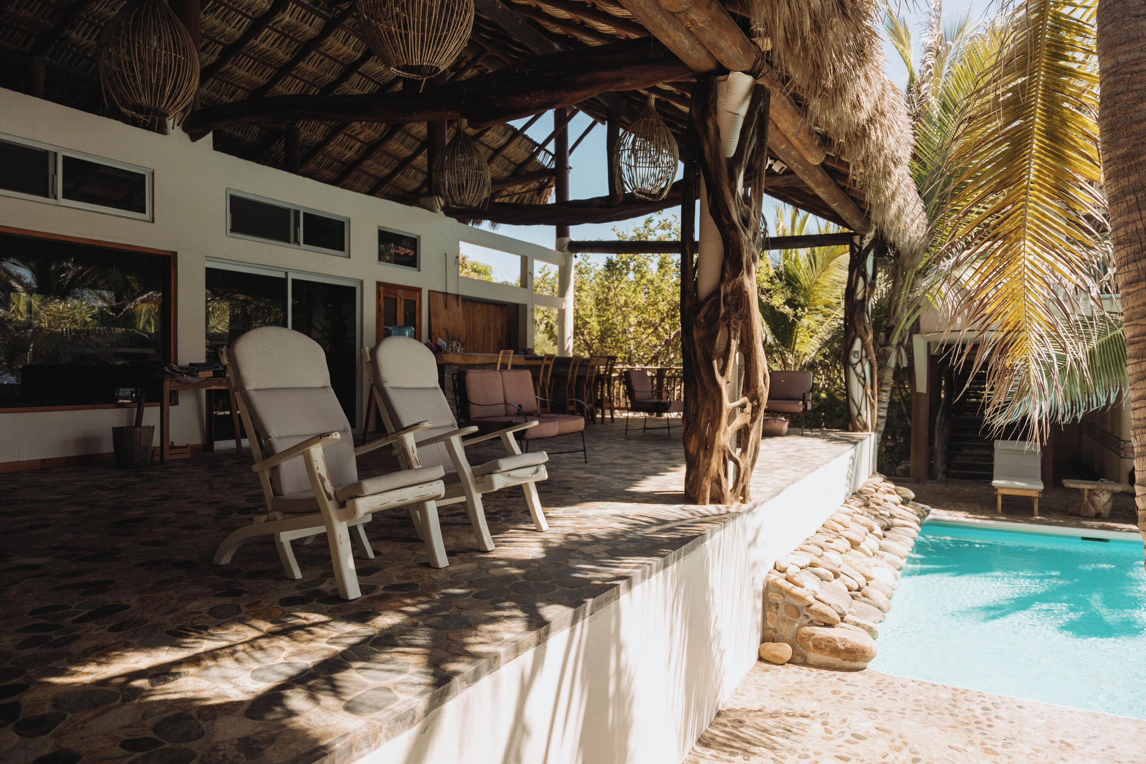 Zona de piscina con sillas de descanso, pared de piedra y vista al estanque.