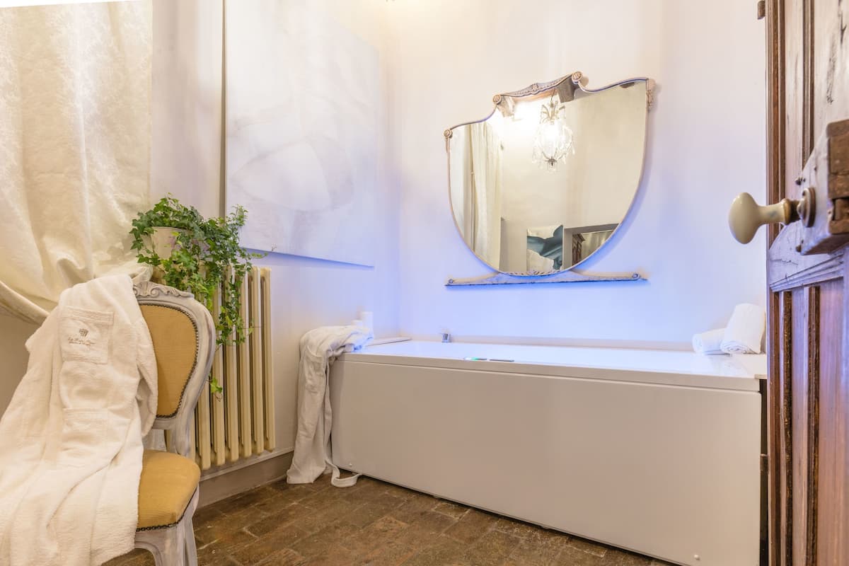 A bathroom with a bathtub, a mirror, a radiator, and a towel rack.
