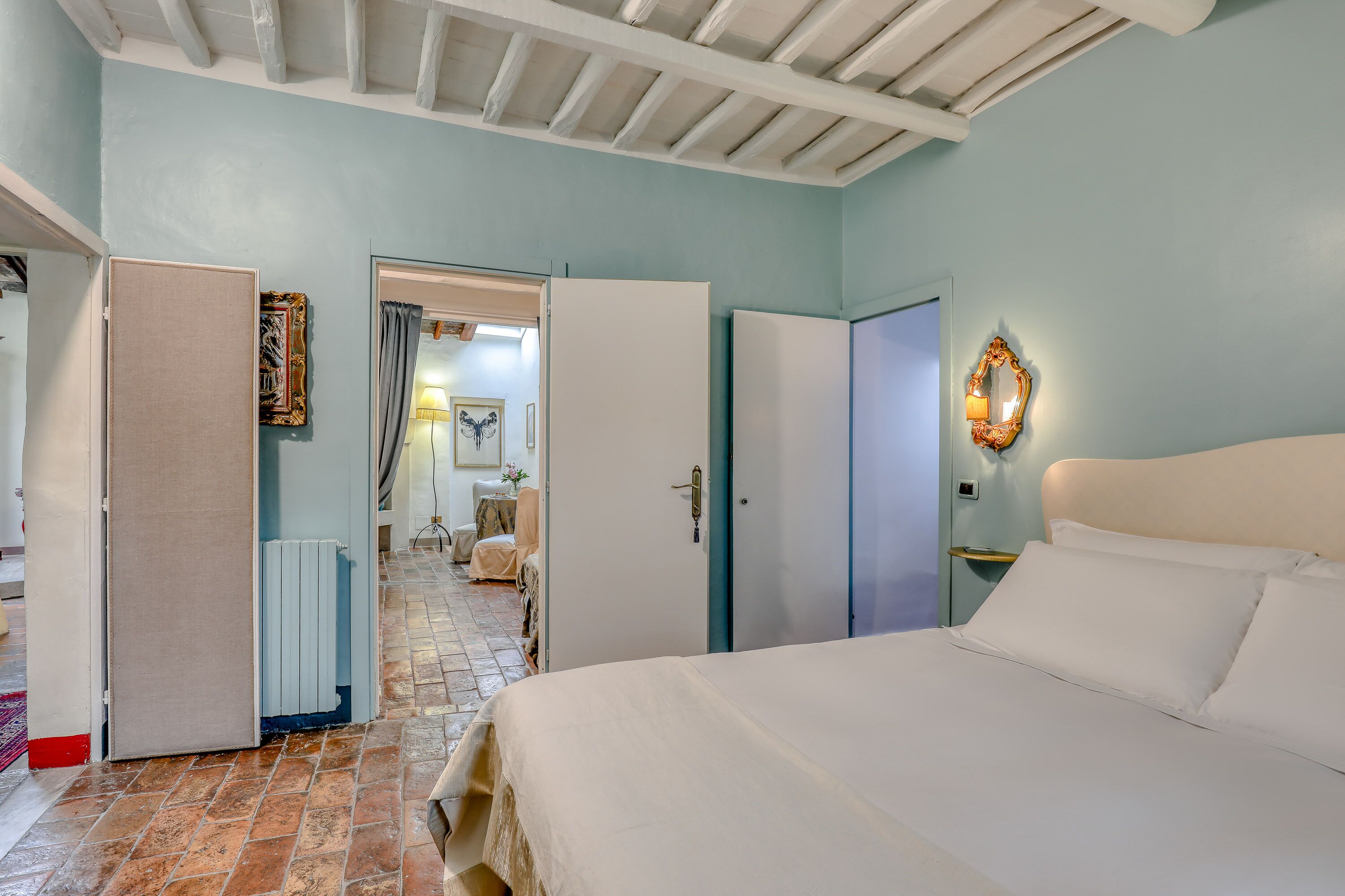 A bedroom with a bed, a wardrobe, a nightstand, and a door leading to a bathroom.