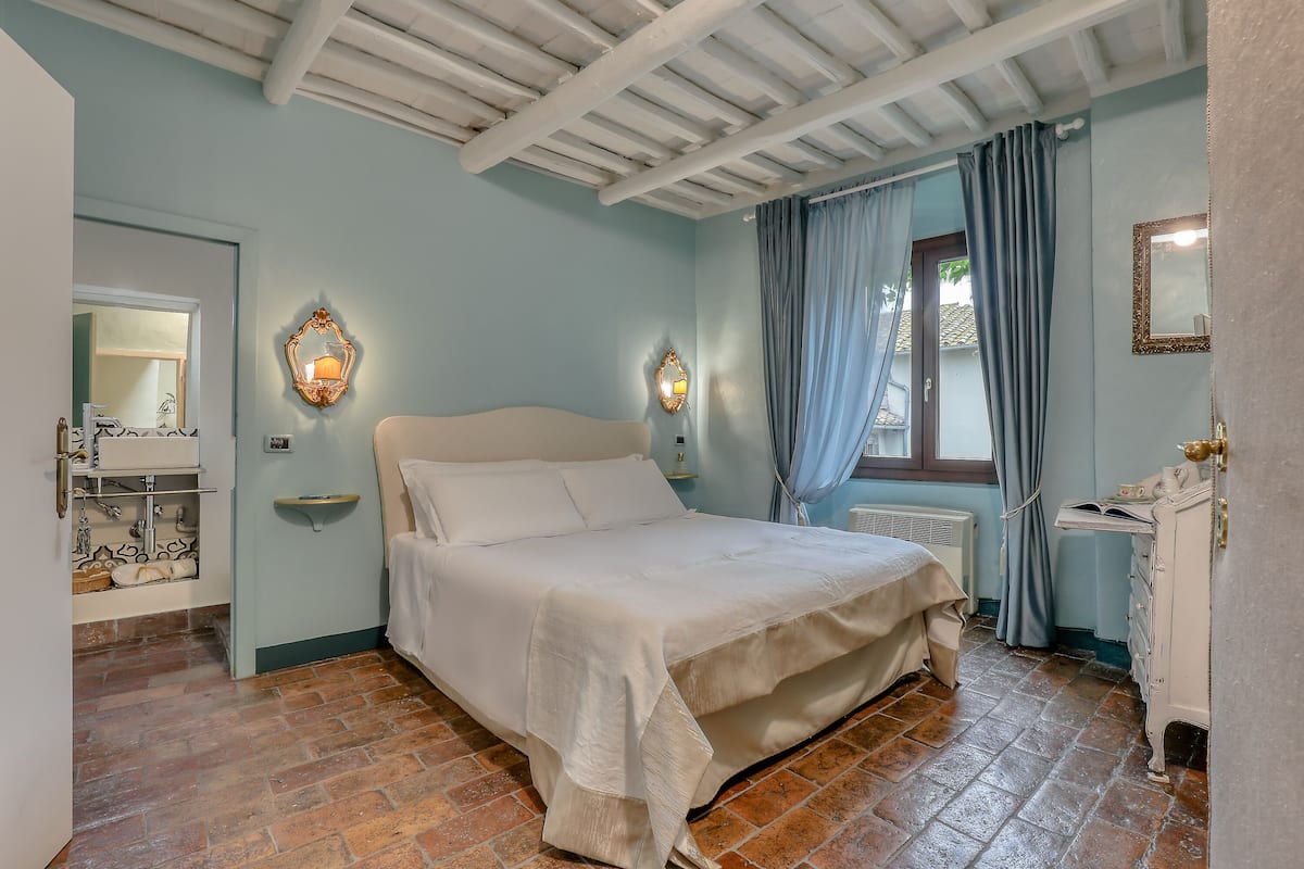 A bedroom with a bed, a dresser, a mirror, and a window with curtains.