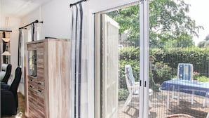 Habitación con puerta corrediza de vidrio que da a un espacio exterior con mesa y sillas.