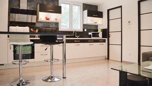 A modern kitchen with a central island, bar stools, and a dining area with a glass table. - Awesome home in Ville di Paraso with WiFi (Ville di Paraso)