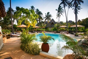 A pool area with lounge chairs, umbrellas, and palm trees. - SeVi Boutique Hotel (Matemwe)