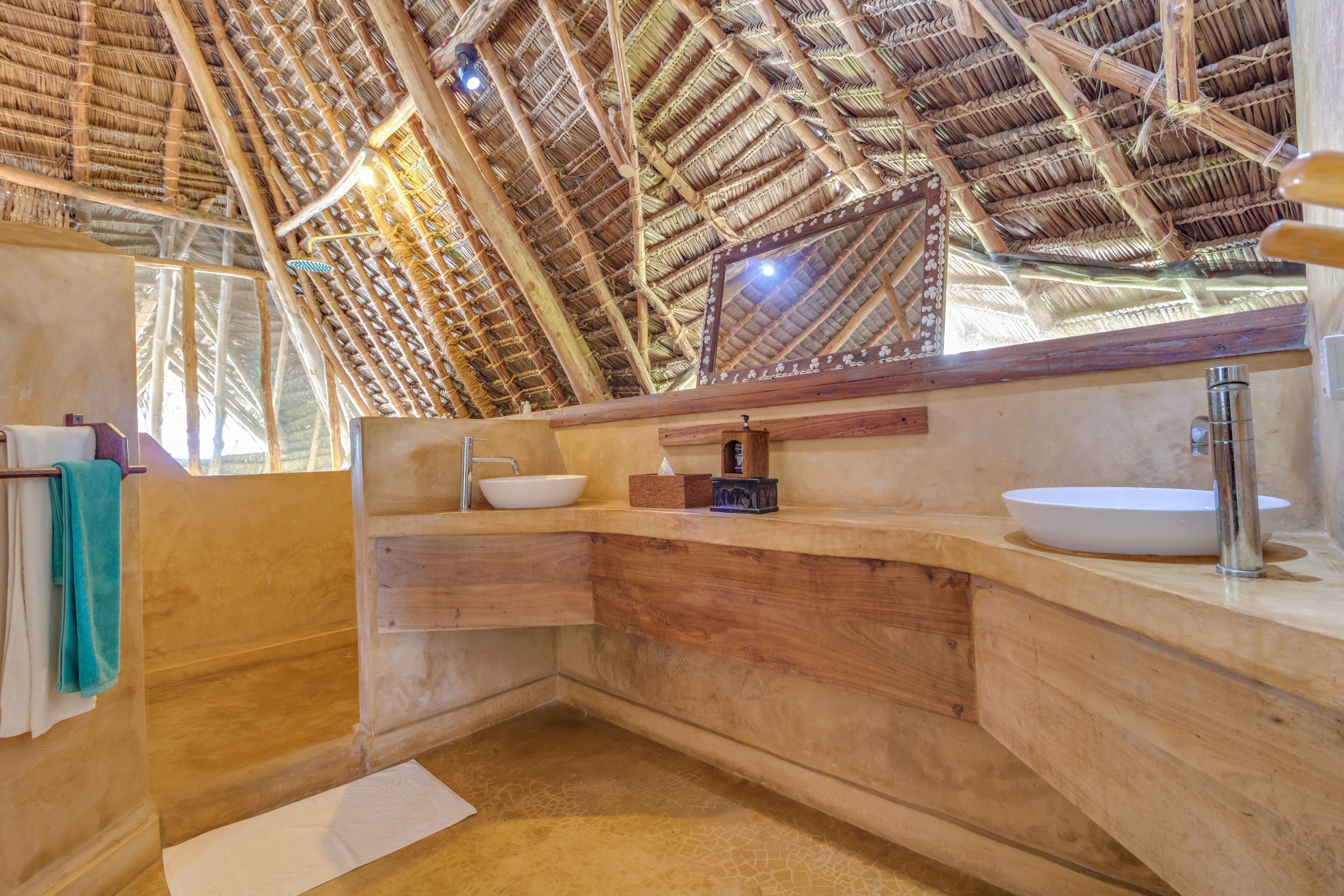 A bathroom with a natural, wooden interior, a large mirror, and a white sink.
