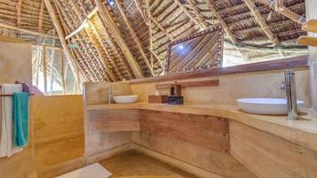 A bathroom with a natural, wooden interior, a large mirror, and a white sink.