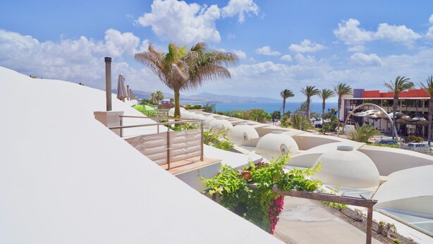 Ein Resort mit weißkuppeligen Strukturen, einer Treppe und Blick auf das Meer.