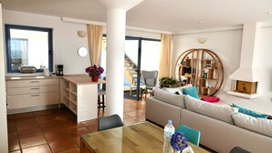 Ein modernes Wohnzimmer mit einer Couch, einem Esstisch und einer Küchenzeile mit einem Fenster.