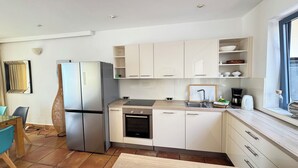 Eine moderne Küche mit weißen Schränken, einem Edelstahlkühlschrank, einem Einbauofen und einem Fenster mit Blick.