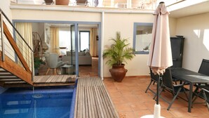 Ein Poolbereich mit Holzterrasse, einem Blumentopf und einem Tisch mit Stühlen.