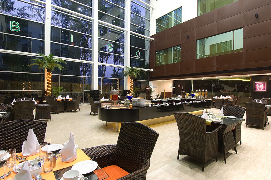 A spacious indoor area with wicker furniture, a buffet setup, and large windows offering views of the outside.