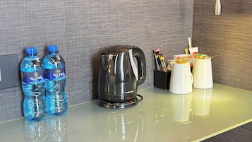 Mostrador de hotel con dos botellas de agua, una cafetera y una taza.