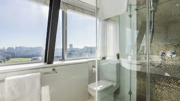 A modern bathroom with a glass shower enclosure, a toilet, and a towel rack.