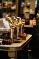 Un buffet avec une machine à café et un récipient rempli de tomates.