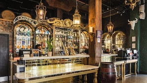 A bar with a marble countertop, shelves with bottles, and a wooden barrel.