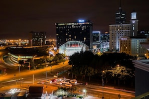 A cityscape at night with a prominent building featuring a large illuminated archway and signage.