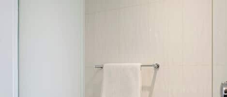 Un baño moderno con cabina de ducha de vidrio, inodoro y toallero.