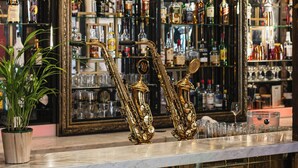 Un bar con decoración elaborada, que incluye un espejo grande, una lámpara colgante y una exhibición de botellas de licores.