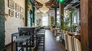 Interior de un restaurante con barra, techo alto con candelabros y vigas de madera.