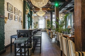 Interior de un restaurante con barra, techo alto con candelabros y vigas de madera.