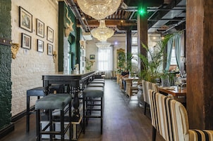 Interior de un restaurante con barra, techo alto con candelabros y vigas de madera.