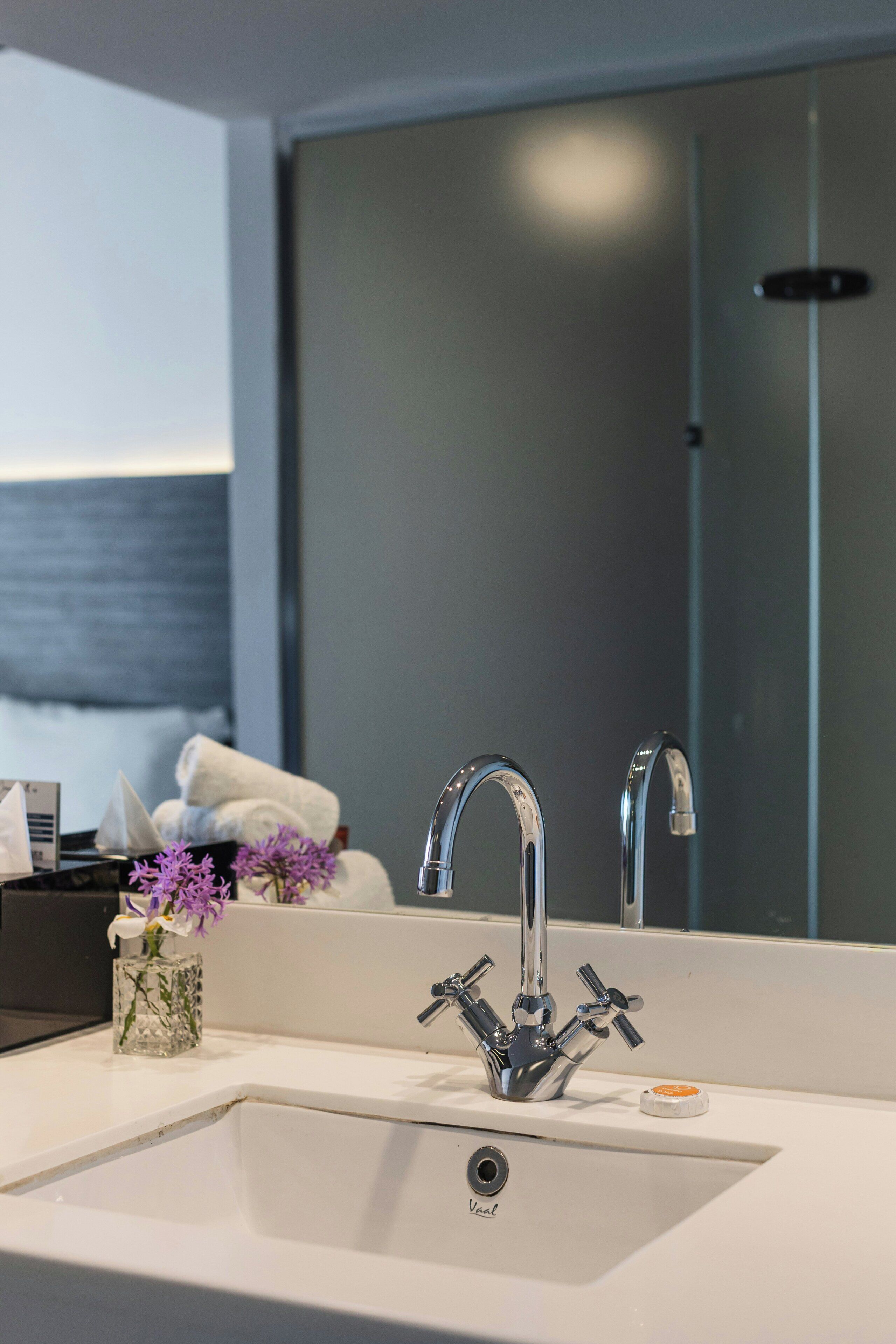 Une salle de bain moderne avec un lavabo blanc, un miroir et un espace douche.