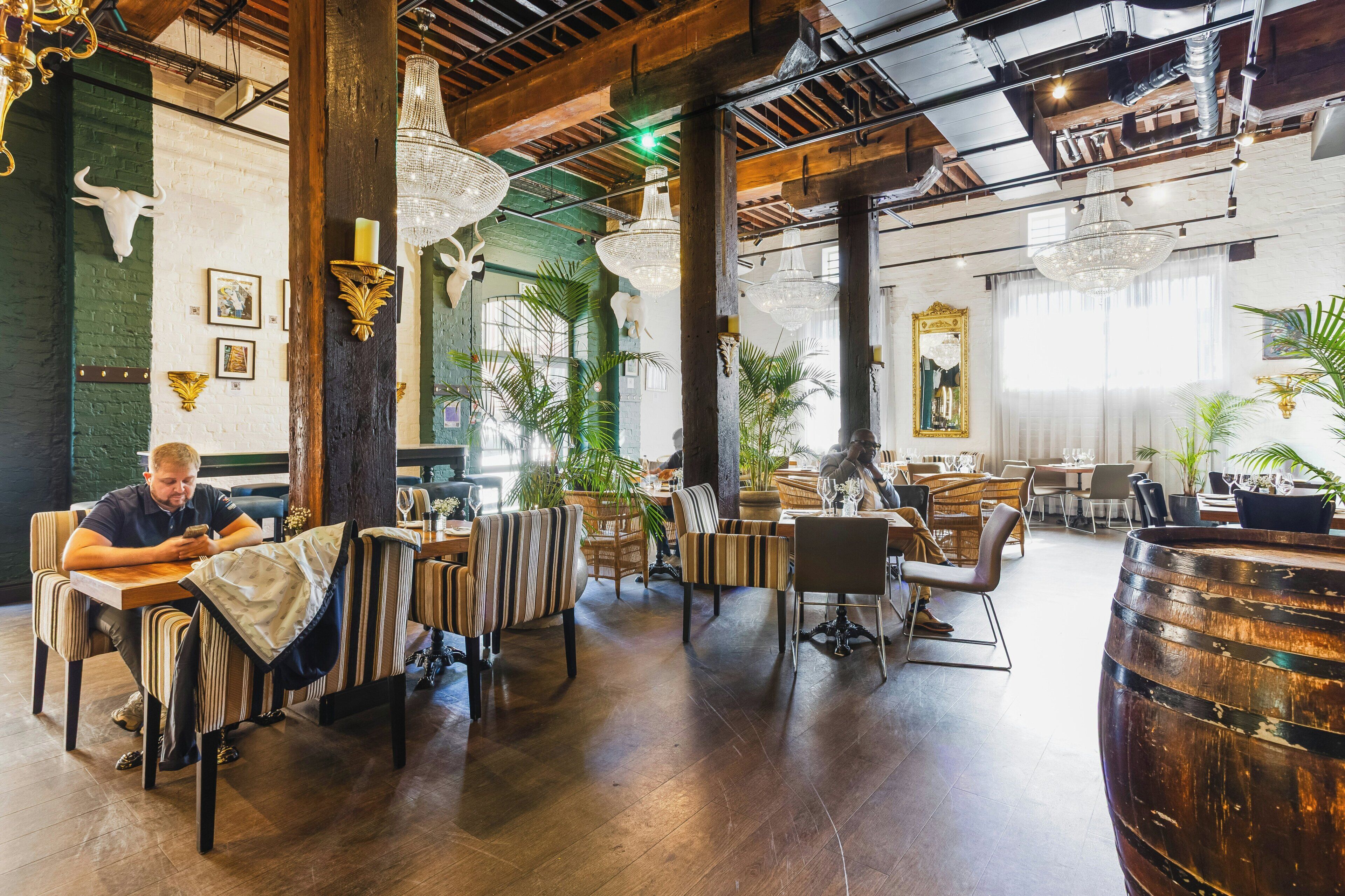 A spacious restaurant with high ceilings, exposed beams, and a mix of modern and classic decor.