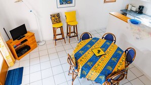 Een eethoek met een tafel, stoelen en een televisie op een houten standaard.