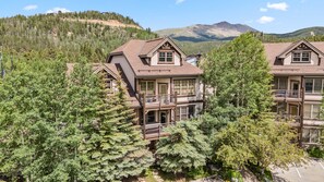 A multi-story hotel with balconies, surrounded by lush greenery and mountains in the background.