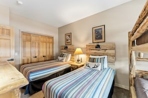Ein Zimmer mit zwei Betten, einem Holzschrank, einem Nachttisch mit Lampe und einem Schlafkoje.