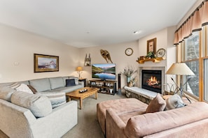 Ein gemütliches Wohnzimmer mit Sofa, Couchtisch, Kamin, Fernseher und Bücherregal.