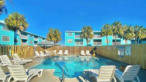 A pool area with lounge chairs and a wooden deck. - Lani Kai Village 211, Beautifully Remodeled Condo with Indirect Gulf Views! (Gulf Shores)