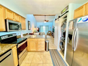 Cocina compacta equipada con microondas, horno y refrigerador, zona de comedor con mesa y sillas, y lavandería con lavadora y secadora.