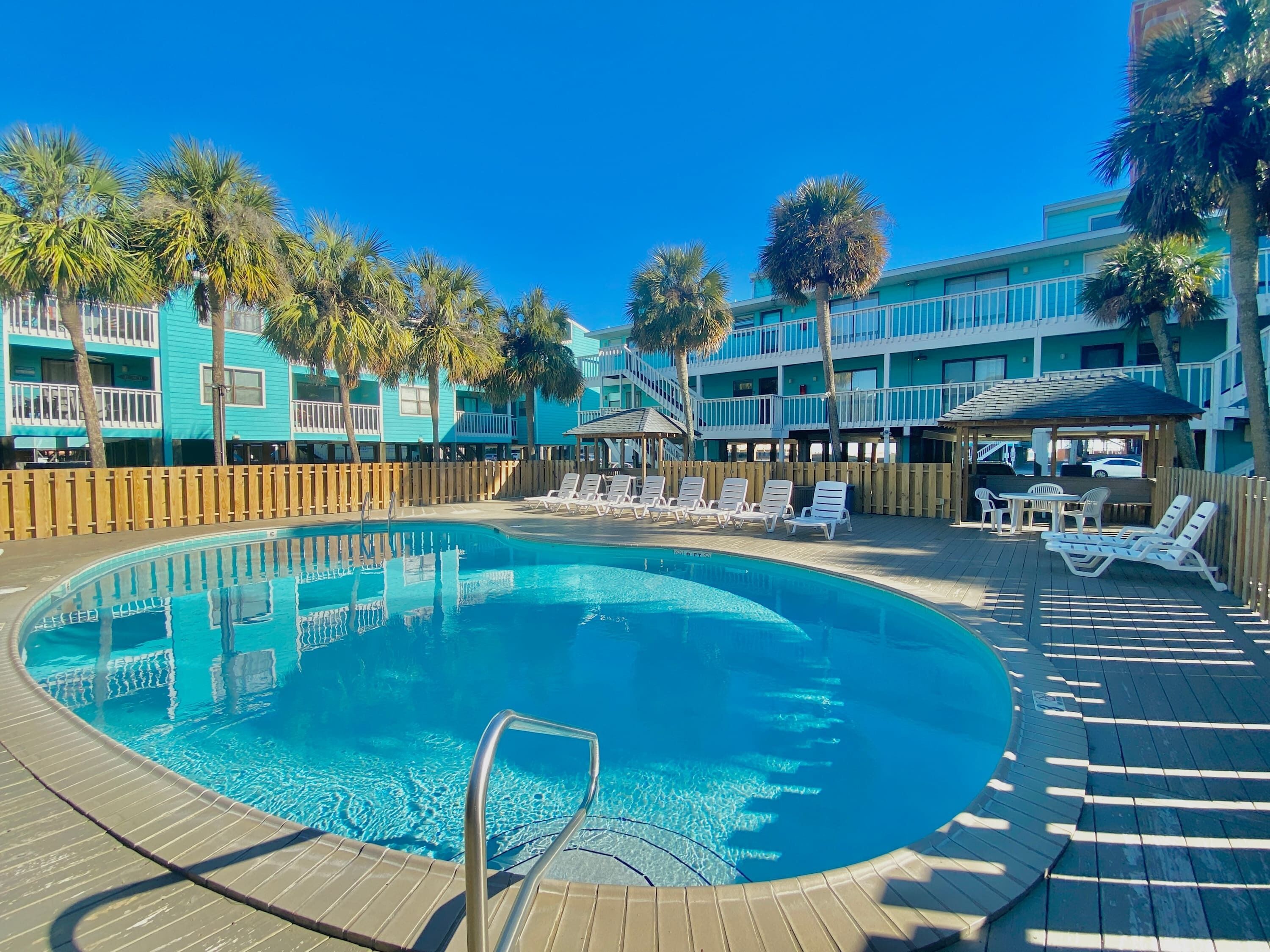 A pool area with lounge chairs and a wooden deck.
