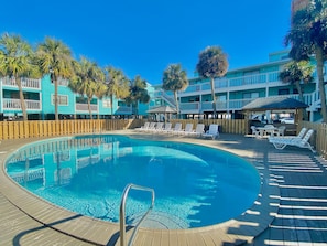 A pool area with lounge chairs and a wooden deck.