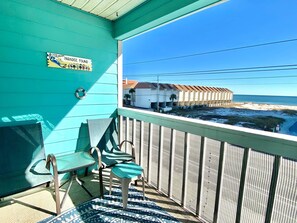 Een turquoise balkon met uitzicht op het strand en een gebouw aan de overkant van het water.